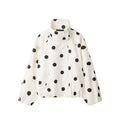 Close-up detail of white polka dot turtleneck jacket — collar and fabric