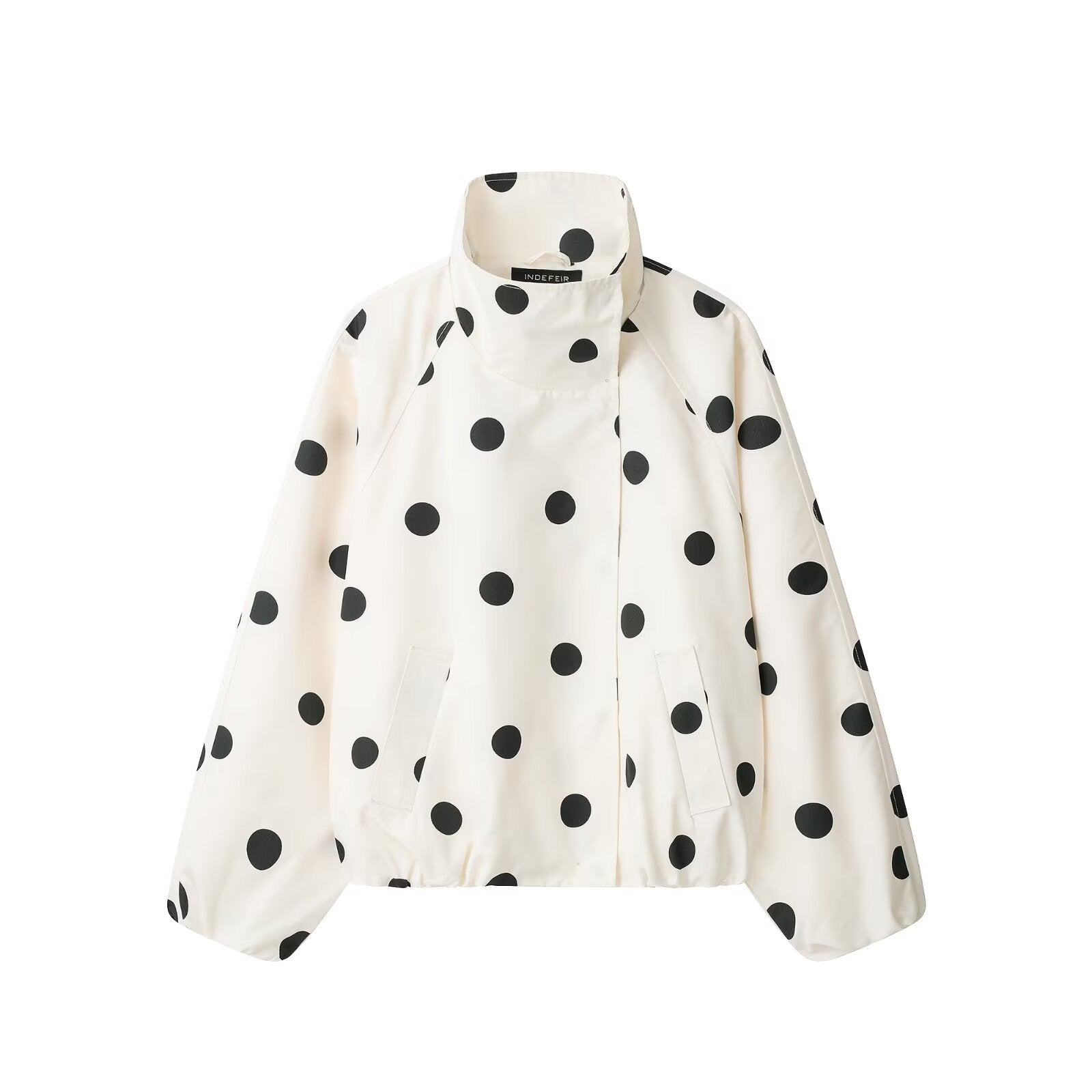 Close-up detail of white polka dot turtleneck jacket — collar and fabric