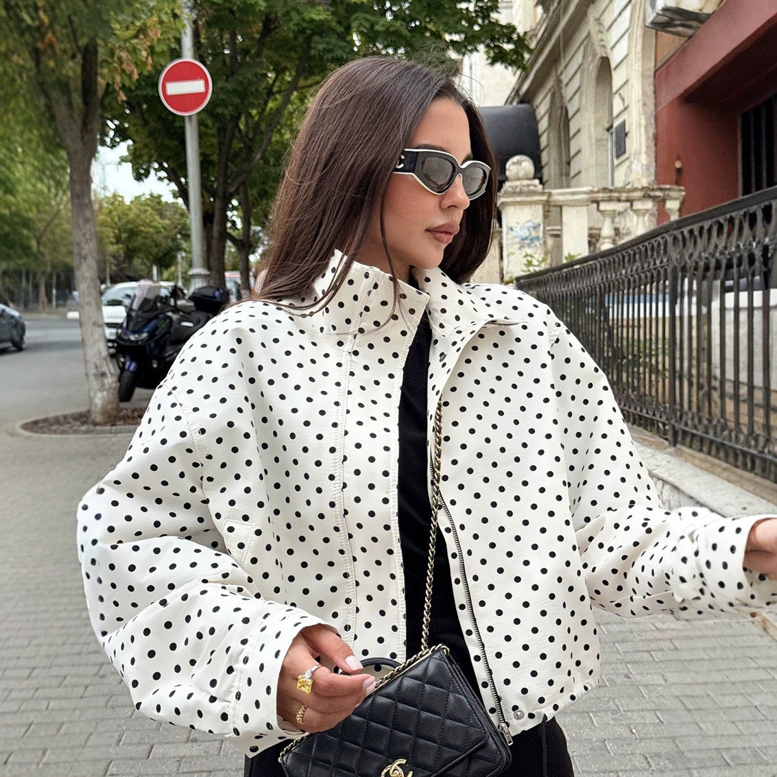 Polka dot cropped jacket in white and black – on model street style front view showing stand collar and zip fastening
