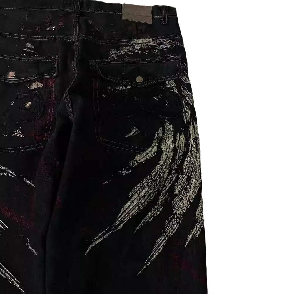FreyaVibe hip hop loose jeans waistband detail — black denim with gold embroidered wing motif and red print close-up